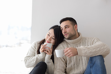 Image showing multiethnic couple enjoying morning coffee by the window