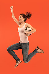 Image showing Forward to the victory.The young woman as soccer football player jumping and kicking the ball at studio on a red