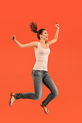 Image showing Freedom in moving. Pretty young woman jumping against orange background