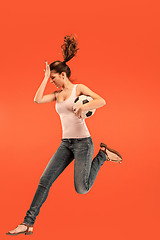 Image showing Forward to the victory.The young woman as soccer football player jumping and kicking the ball at studio on a red