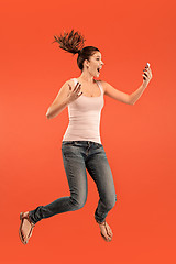 Image showing Full length of pretty young woman with mobile phone while jumping