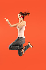 Image showing Full length of pretty young woman with mobile phone while jumping