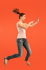 Image showing Full length of pretty young woman with mobile phone while jumping