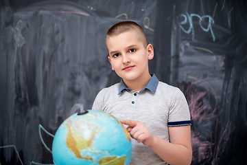 Image showing boy using globe of earth in front of chalkboard