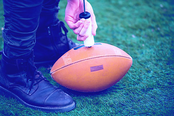 Image showing man pumping air into american football ball