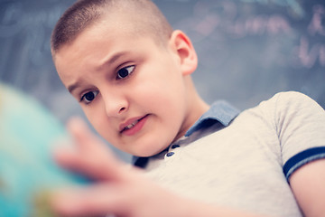 Image showing boy using globe of earth in front of chalkboard