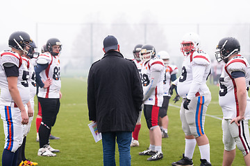 Image showing american football players discussing strategy with coach