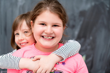 Image showing little girls hugging in front of chalkboard