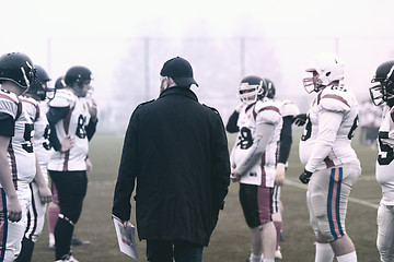 Image showing american football players discussing strategy with coach