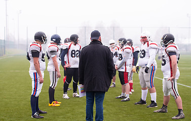 Image showing american football players discussing strategy with coach