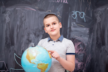 Image showing boy using globe of earth in front of chalkboard