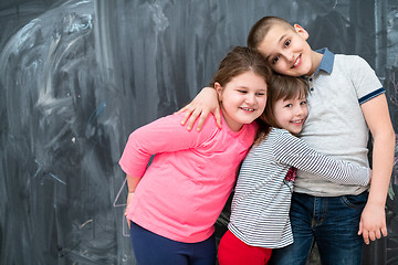 Image showing group of kids hugging in front of chalkboard
