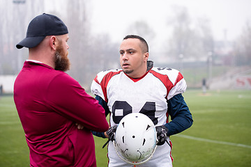 Image showing american football player discussing strategy with coach