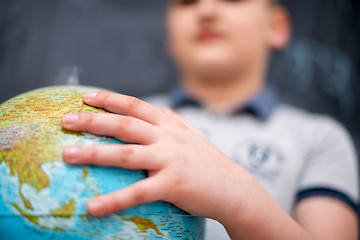 Image showing boy using globe of earth in front of chalkboard