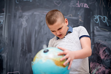 Image showing boy using globe of earth in front of chalkboard