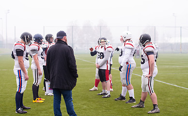 Image showing american football players discussing strategy with coach