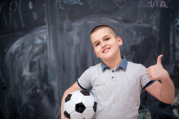 Image showing happy boy holding a soccer ball in front of chalkboard