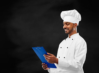 Image showing chef reading menu on clipboard over chalkboard