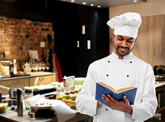 Image showing happy male indian chef reading cookbook at kitchen