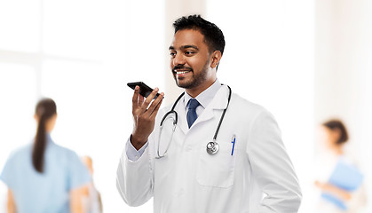 Image showing smiling indian male doctor calling on smartphone