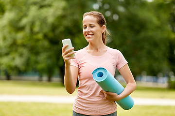 Image showing woman with exercise mat and smartphone at park