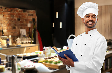 Image showing happy male indian chef with cookbook at kitchen