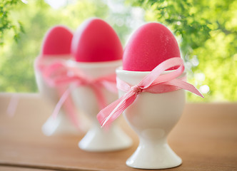 Image showing pink colored easter eggs in holders on table