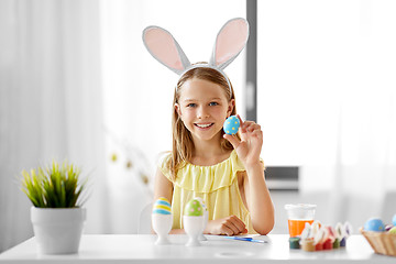 Image showing happy girl coloring easter eggs at home