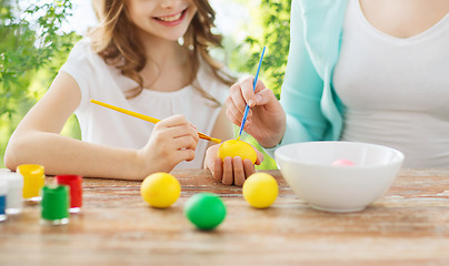 Image showing happy smiling girl and mother coloring easter eggs