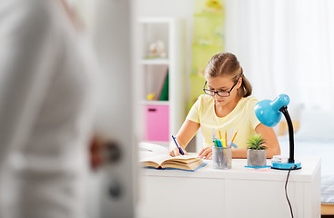 Image showing schoolgirl doing homework and mother entering room