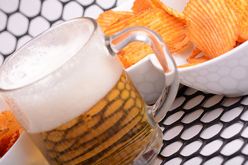 Image showing Glass of light beer and potato chips on a abstract background