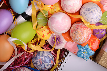 Image showing Handcrafted easter eggs close up, white notepad, ribbons and decoration