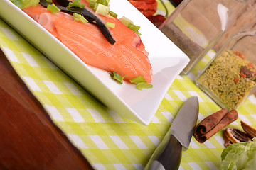 Image showing fresh salmon fillet on white plate. knife, red pepper, cinnamon and lemon