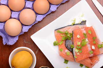 Image showing fresh salmon fillet close up on white plate. eggs and lemon