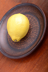 Image showing Lemons in a brown bowl on a wooden background