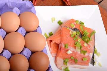 Image showing fresh salmon fillet close up on white plate. red pepper, eggs and lemon