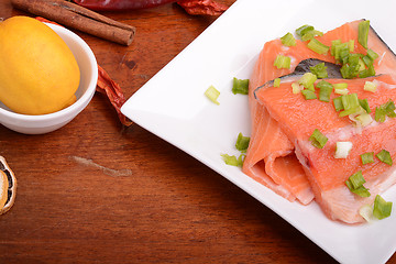 Image showing fresh salmon fillet on white plate. red pepper, cinnamon and lemon