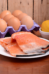 Image showing fresh salmon fillet close up on white plate. eggs and lemon