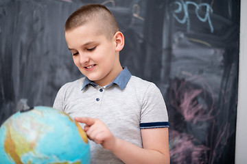 Image showing boy using globe of earth in front of chalkboard