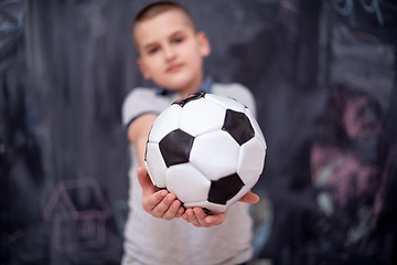 Image showing happy boy holding a soccer ball in front of chalkboard