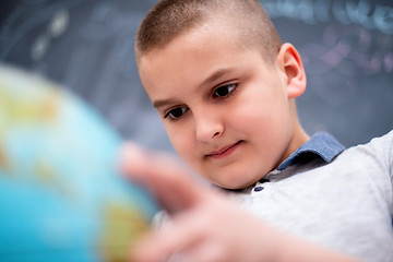 Image showing boy using globe of earth in front of chalkboard