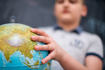 Image showing boy using globe of earth in front of chalkboard