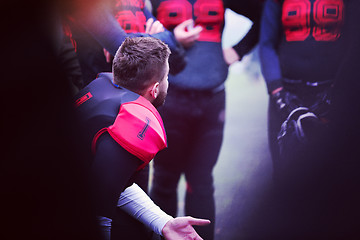 Image showing american football player discussing strategy with his team