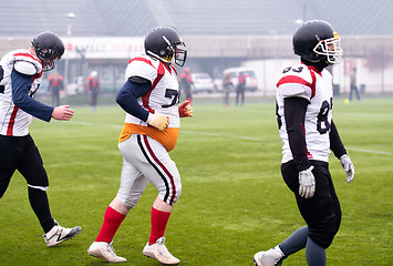 Image showing confident American football players leaving the field