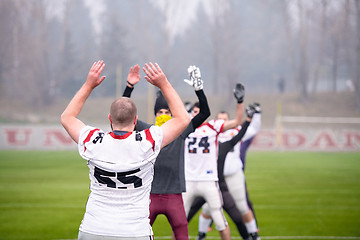 Image showing american football players stretching and warming up