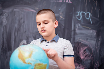 Image showing boy using globe of earth in front of chalkboard