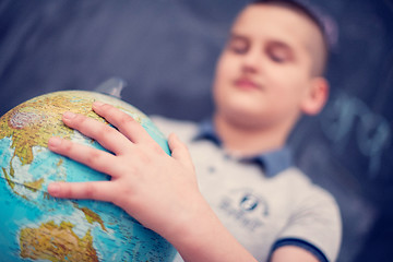 Image showing boy using globe of earth in front of chalkboard