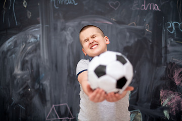 Image showing happy boy holding a soccer ball in front of chalkboard