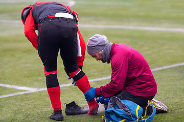 Image showing Sports doctor using freezing spray while treating injured sportm