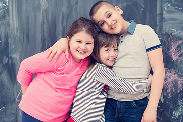 Image showing group of kids hugging in front of chalkboard